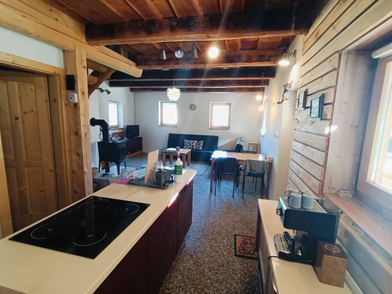 Chata s dřevěnými prvky a kachlemi, podlaha s dřevěným dekorem, kuchyňský ostrůvek.