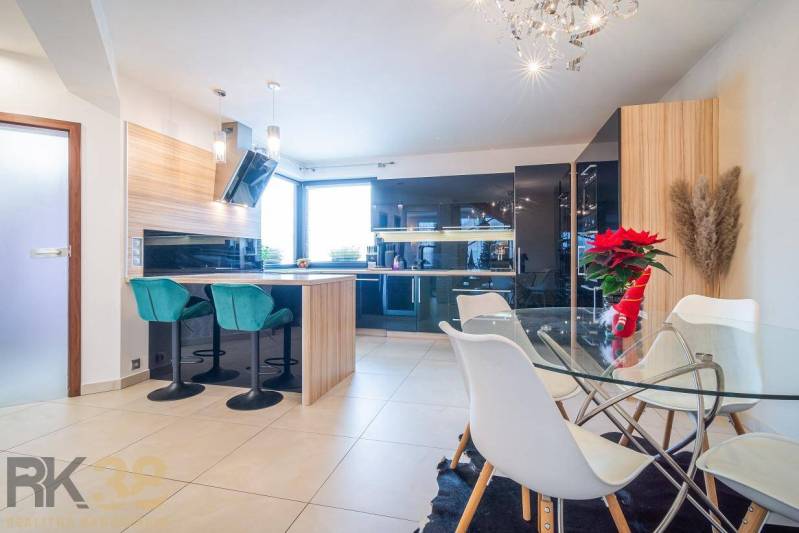 Světlá kuchyně s jídelním stolem a barovými židlemi v rodinném domě.