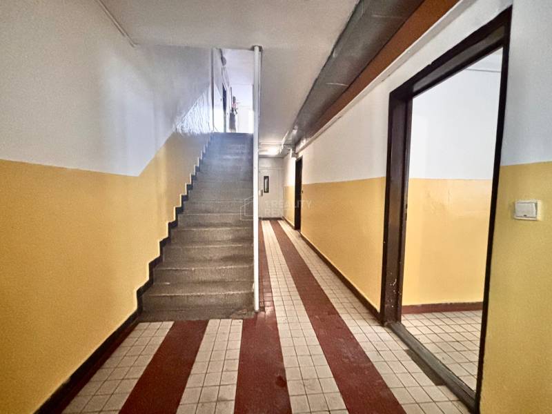 Vstupní chodba s dlažbou v 3-pokojovém bytě, schodiště a barevné stěny.