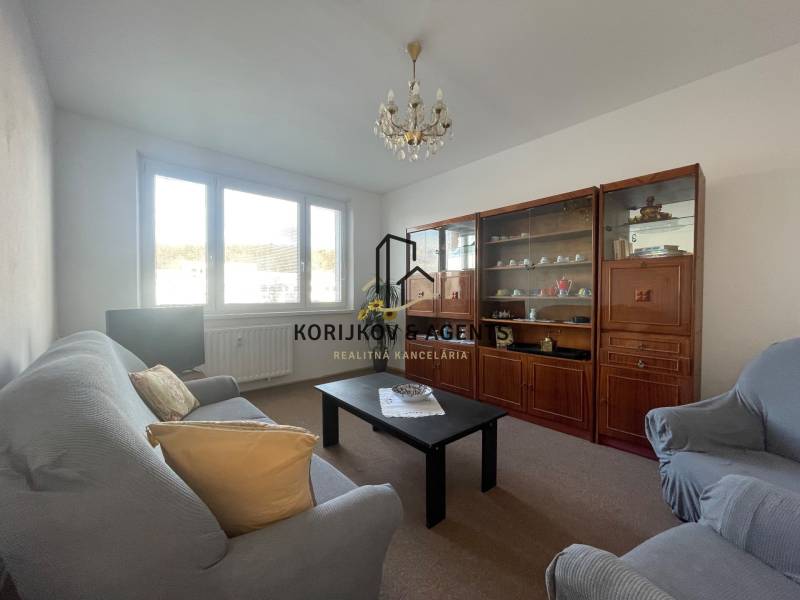 Obývací pokoj v 3pokojovém bytě s pohovkou, křesly a obývací stěnou.