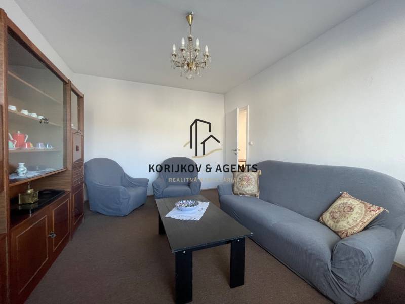 Obývací pokoj v 3pokojovém bytě s pohodlnou pohovkou, křesly a vitrínou.