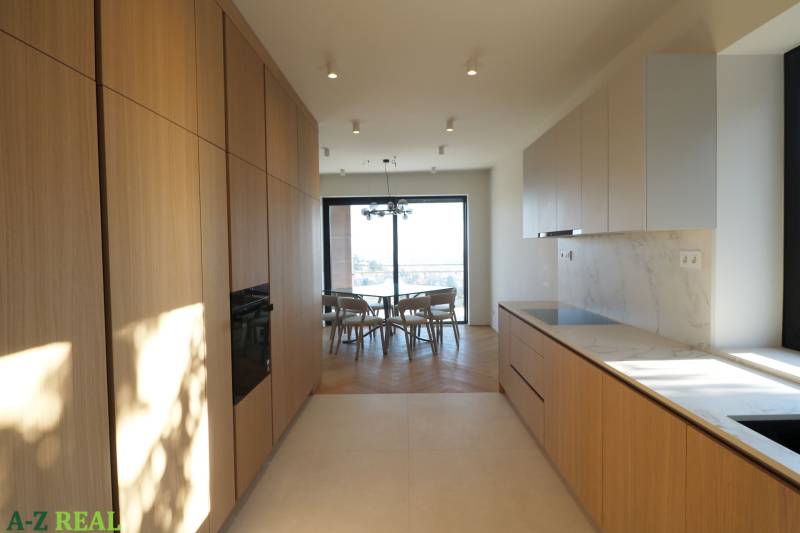 Kuchyně ve 4-pokojovém bytě s podlahou s dřevěným dekorem a světlou kuchyňskou linkou.