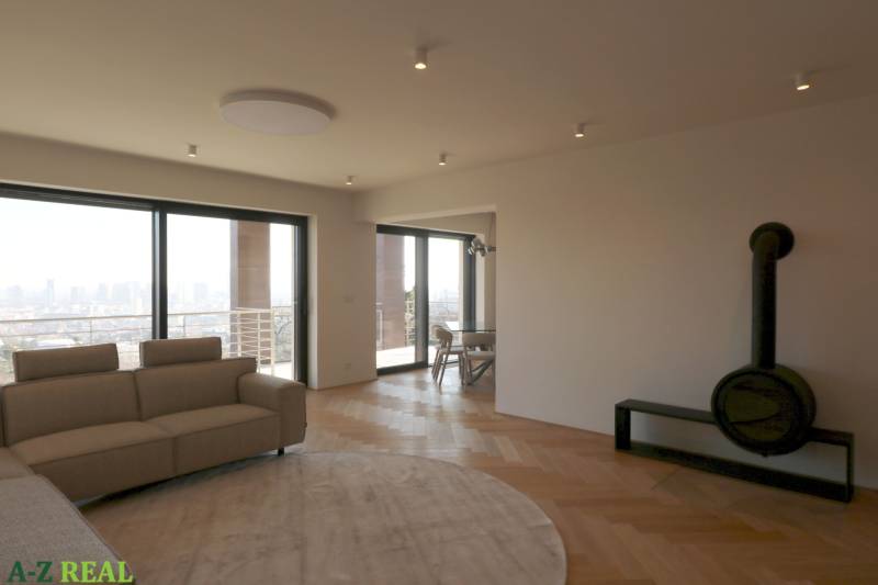 Obývací pokoj s pohovkou, krbem a podlahou s dřevěným dekorem ve 4pokojovém bytě.