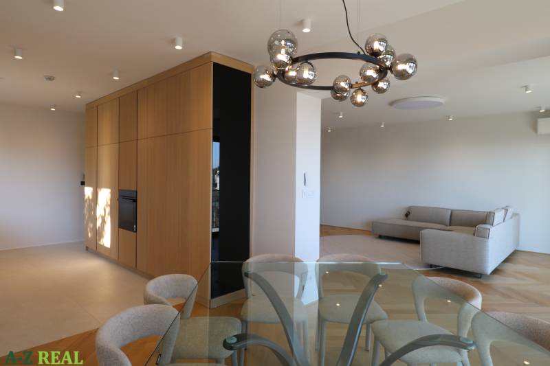 Obývací pokoj s jídelním stolem, pohovkou a svítidlem ve 4pokojovém bytě, podlaha s dřevěným dekorem.