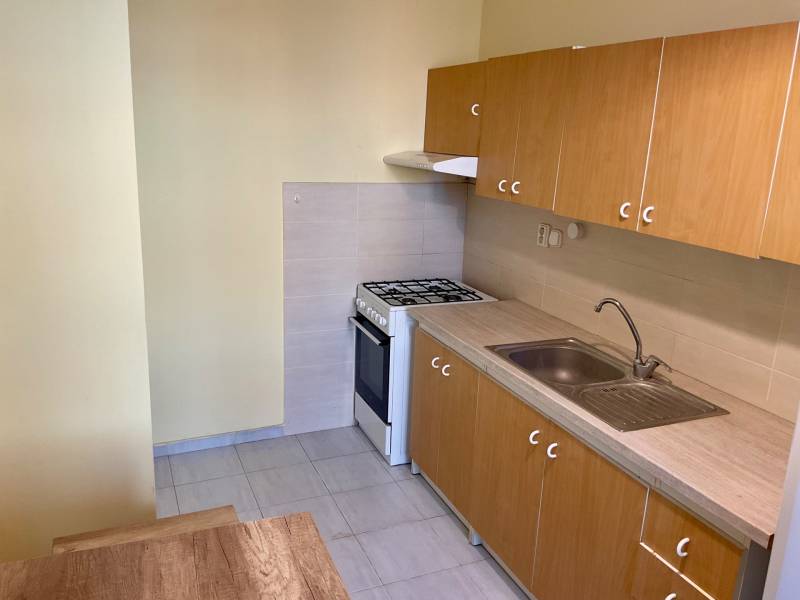 Kuchyně v 3-pokojovém bytě s plynovým sporákem a dřevěnými skříňkami.