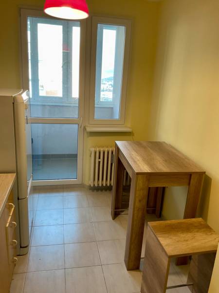 Kuchyně v 3-pokojovém bytě s velkými okny, barovým stolem a židlemi.