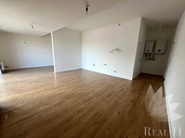 Interiér 2-pokojového bytu s podlahou s dřevěným dekorem, bílé stěny, otevřený prostor.