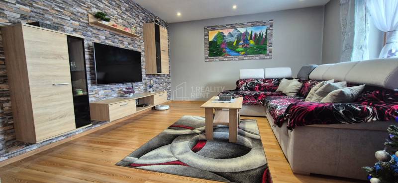 Obývací pokoj v rodinném domě s podlahou s dřevěným dekorem, kamenem na stěně a pohodlnou sedačkou.