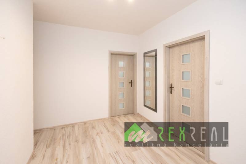 Chodba v 3-pokojovém bytě s podlahou s dřevěným dekorem a zrcadlem.