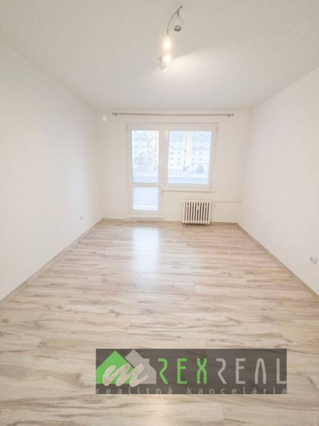 Světlá místnost s podlahou s dřevěným dekorem v 3-pokojovém bytě.