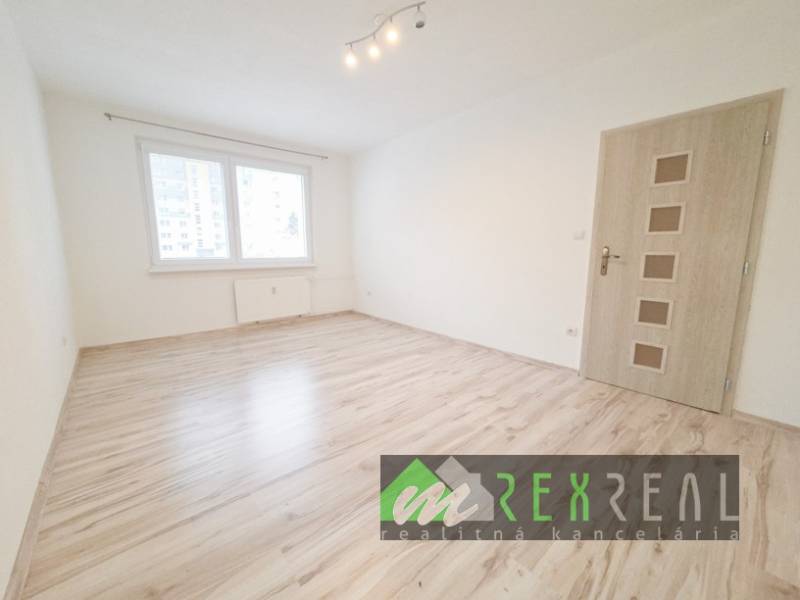 Pokoj v 3pokojovém bytě s podlahou s dřevěným dekorem a oknem.