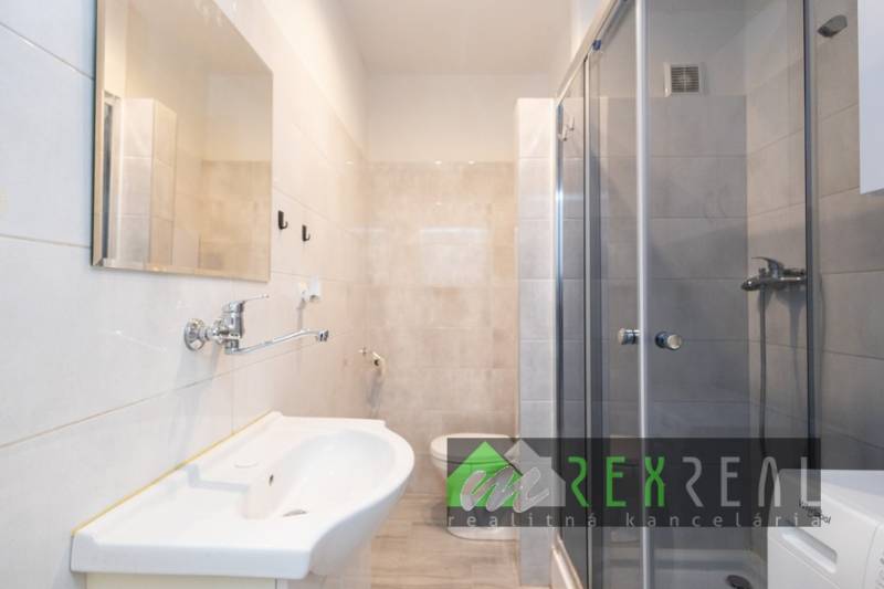 Koupelna v 3-pokojovém bytě se sprchovým koutem, umyvadlem a světlými dlaždicemi.