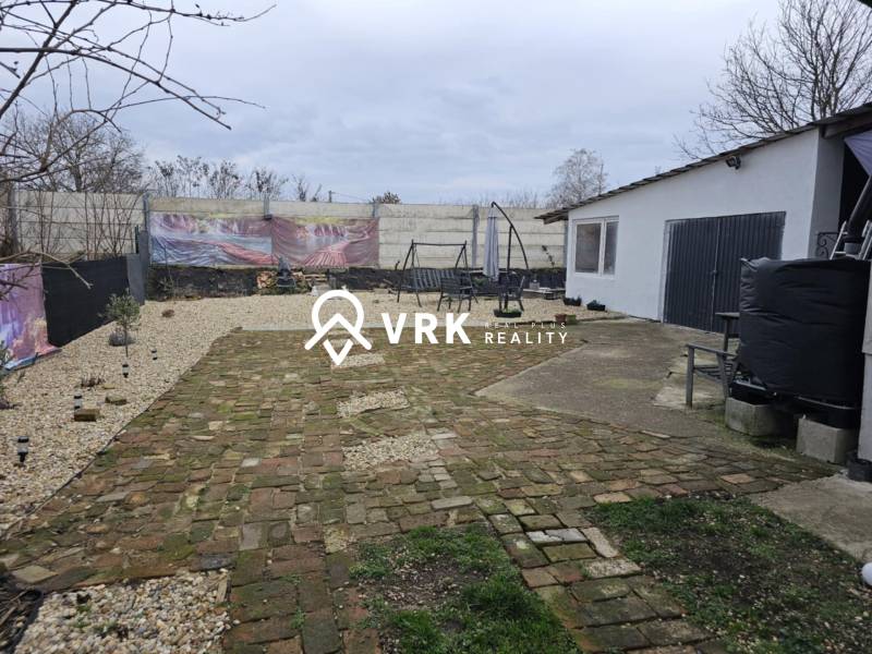 Dvůr rodinného domu v Hernádkaku s dlažbou a venkovním posezením na pozemku.