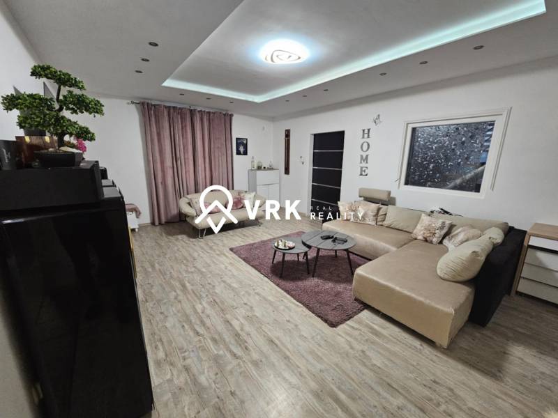 Obývací pokoj v rodinném domě s podlahou s dřevěným dekorem a velkou sedačkou.