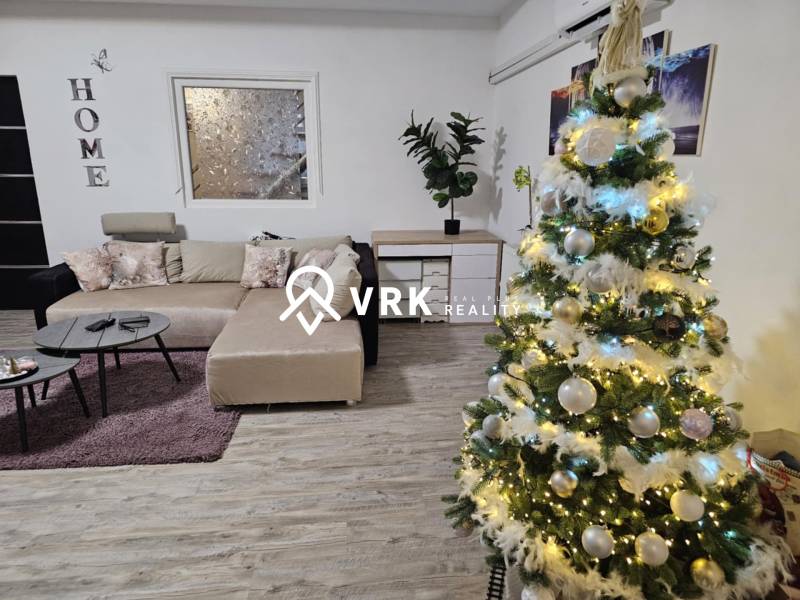 V rodinném domě s podlahou s dřevěným dekorem je ozdobený vánoční stromeček a sedačka.