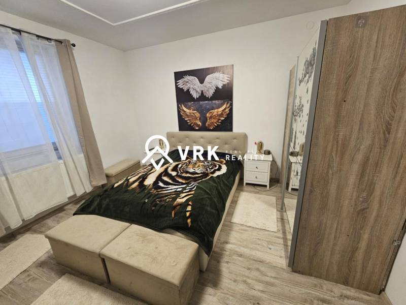 Ložnice s postelí, skříní a podlahou s dřevěným dekorem v rodinném domě.