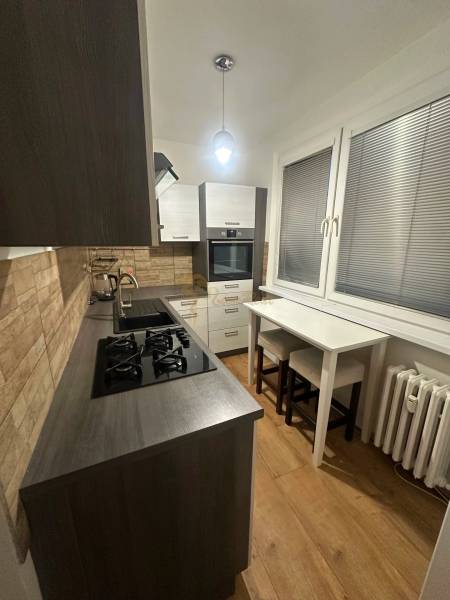 Kuchyně v 2-pokojovém bytě s podlahou s dřevěným dekorem a plynovým sporákem.