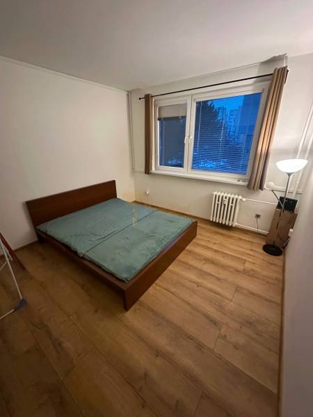 Ložnice v 2-pokojovém bytě s postelí a podlahou s dřevěným dekorem.