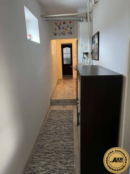 Úzká chodba v rodinném domě, kobereček se vzorem a výzdoba stěn.