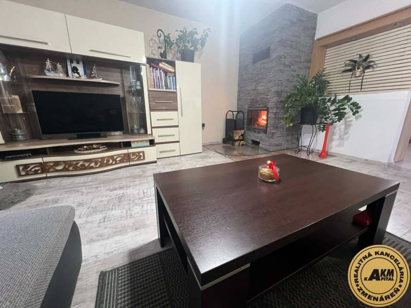 Obývací pokoj v rodinném domě s krbem a nábytkovou stěnou, podlaha s dřevěným dekorem.