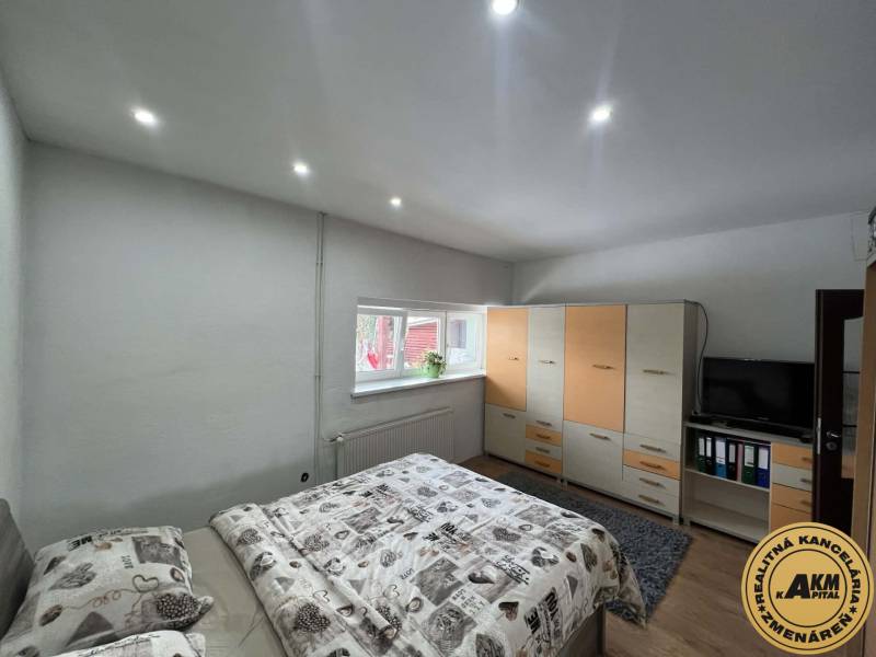 Ložnice v rodinném domě s postelí, skříní a televizí. Podlaha s dřevěným dekorem.