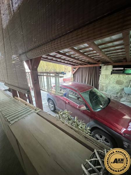 Červené auto zaparkované pod přístřeškem u rodinného domu na Dubovské ulici ve Zvolenu.