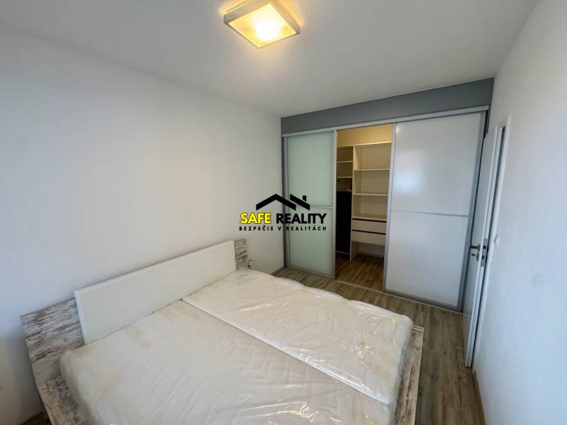 Ložnice s manželskou postelí, vestavěnou skříní a podlahou s dřevěným dekorem v 2pokojovém bytě.