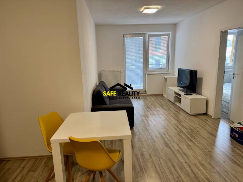 Obývací pokoj dvoupokojového bytu s podlahou s dřevěným dekorem a světlým posezením.