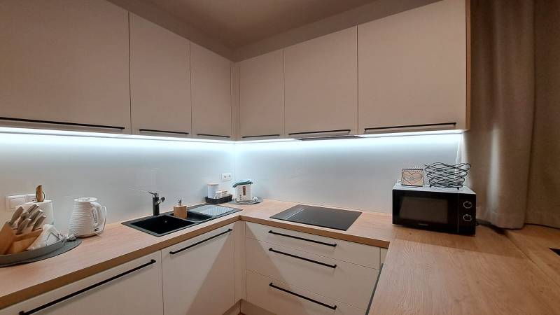 Kuchyně v 2-pokojovém bytě s dřevěným dekorem a vybavením na vaření.