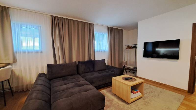 Obývací pokoj v 2pokojovém bytě s pohodlnou sedací soupravou a podlahou s dřevěným dekorem.