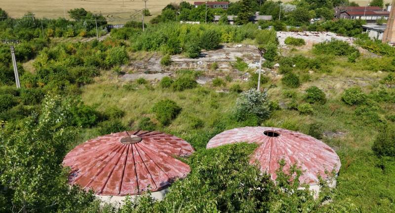 Komerční pozemky v Ivance pri Nitře s kruhovými střechami, obklopené bujnou zelení.