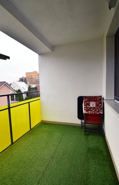 Balkon 2-pokojového bytu v Trenčíně na Dolním Šianci, umělý trávník a židle.