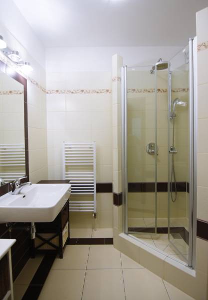 Koupelna se sprchovým koutem a umyvadlem v 2-pokojovém bytě s dlažbou.