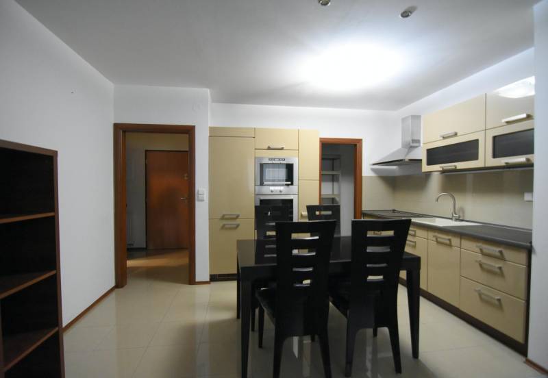 Kuchyně v 2-pokojovém bytě se zabudovanými spotřebiči a jídelním stolem.