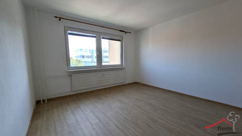 Pokoj v 1-pokojovém bytě s podlahou s dřevěným dekorem a velkým oknem.