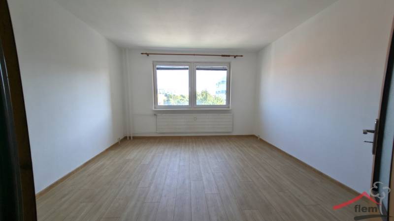 Prázdný pokoj s podlahou s dřevěným dekorem a velkým oknem v 1-pokojovém bytě.