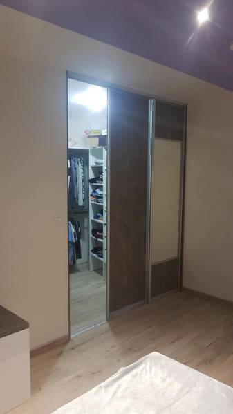 Šatník s posuvnými dveřmi a podlahou s dřevěným dekorem v rodinném domě.