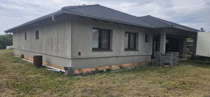 Rodinný dům z neomítnutých zdí v Semerově s šindelovou střechou na travnatém pozemku.