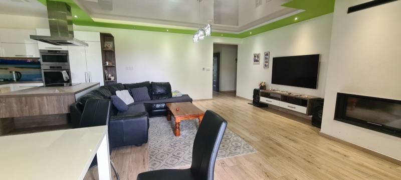 Obývací pokoj v rodinném domě s koženou sedačkou, televizorem a podlahou s dřevěným dekorem.