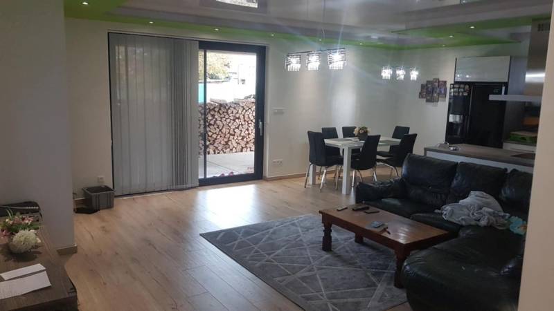 Obývací pokoj v rodinném domě s podlahou s dřevěným dekorem, pohovkou a jídelním stolem.