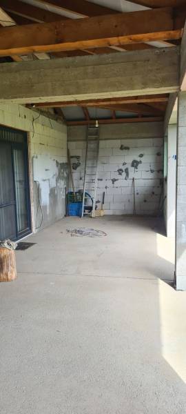 Interiér rodinného domu s nevkusnými stěnami, žebříkem a stavebním materiálem.