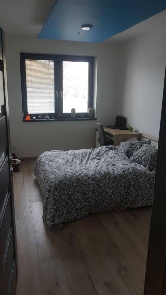 Ložnice v rodinném domě s postelí, pracovním stolem a podlahou s dřevěným dekorem.