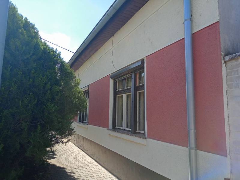 Rodinný dům v Nových Zámcích se sítěmi na zateplené fasádě a stromem u chodníku.