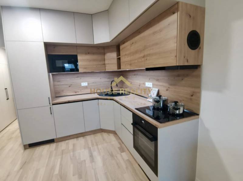 Kuchyně v 1-pokojovém bytě s podlahou s dřevěným dekorem a moderními spotřebiči.