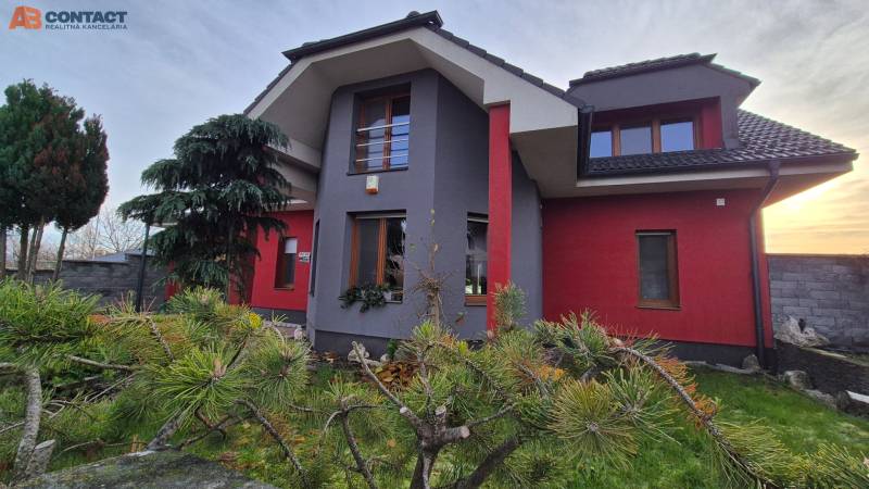 Rodinný dům na Větrné ulici v Krakovanech, obklopený stromy a upravenou zahradou.