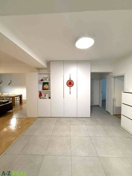 Chodba ve 4-pokojovém bytě s bílými vestavěnými skříněmi a keramickou dlažbou.