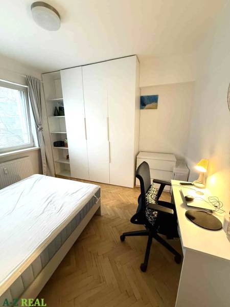 Ložnice ve 4-pokojovém bytě s bílým nábytkem a podlahou s dřevěným dekorem.