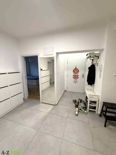 Vstupní hala 4pokojového bytu s dlažbou a nástěnným zrcadlem.