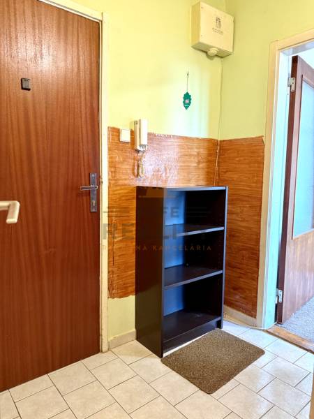 Vstupní chodba 1-pokojového bytu se skříní, dlažbou a telefonem na stěně.