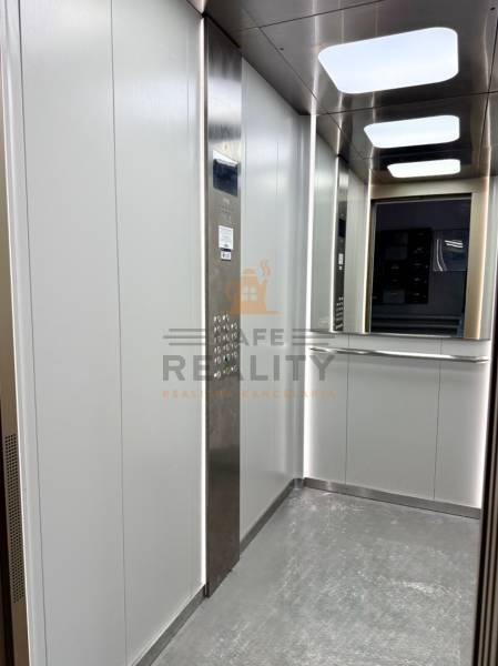 Interiér výtahu s nerezovým panelem a zrcadlem v 1-pokojovém bytě.